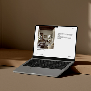 Laptop on a wooden surface with a minimalistic design on the screen showing design philosophy page of an investment guide template for interior designers
